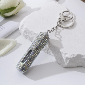 Detail of 5ml rhinestone perfume atomizer keychain on elegant white stone background