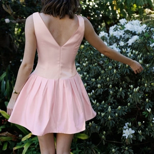 Rear view of pink satin sleeveless dress with V-neck and pleated skirt detail