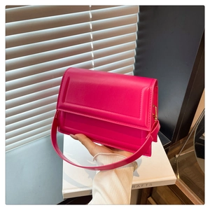 Detail shot of the rose pink PU leather shoulder bag held against a soft indoor background