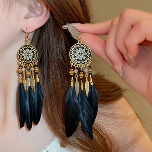 Detailed close-up of Bohemian gold-tone earrings with black feathers and ethnic beads