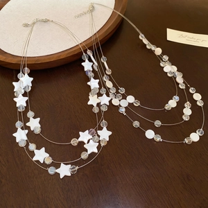 Collier multi-rangs en nacre et cristal avec pendentifs étoiles sur fond en bois