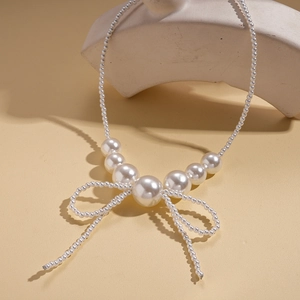 Close-up of elegant faux pearl bow pendant necklace with vintage French style details