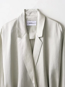 Dettaglio ravvicinato del rever di un elegante blazer verde salvia chiaro effetto lino