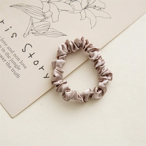 Close-up of champagne satin scrunchie with silk texture and elastic inner band detail