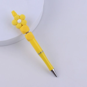 Detail of yellow flower silicone beaded pen with silver metal tip on a white plate