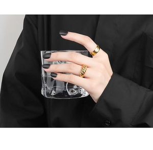 Detailed view of layered 18K gold croissant twisted and wide flat rings on fingers