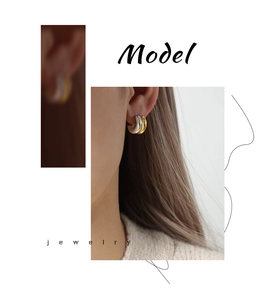Detail of two-tone gold and silver C-shaped polished earrings worn by a female model