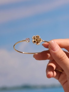 Close-up of golden starfish flower open bangle with 5A zircon inlay against blue sky