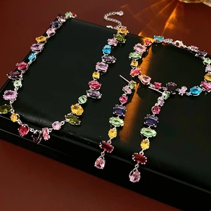 Detail of colorful zircon teardrop pendant necklace and stud earrings set in silver finish