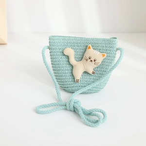 Detail of mint green woven straw bag featuring a cute 3D cartoon cat patch for kids