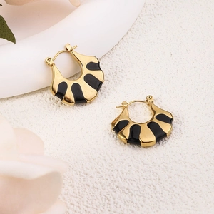 Detail of fan-shaped gold-plated earrings with black enamel finish on textured surface