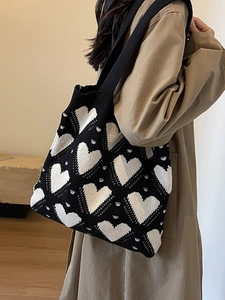 Knitted heart pattern tote bag in black and white shown on model shoulder