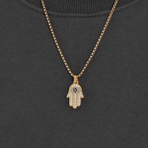 Gold Hamsa Hand pendant necklace with full CZ stones on a gold box chain worn by a model