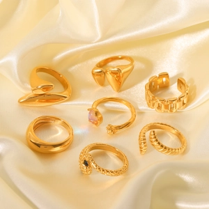 Macro shot of gold stainless steel ring set with diverse geometric textures on silk