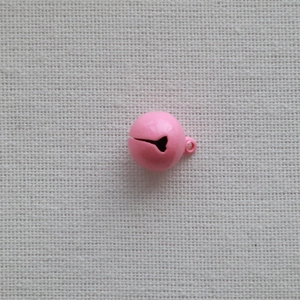 Close-up of a 14mm pink metal pet bell with a hanging loop on a beige fabric background