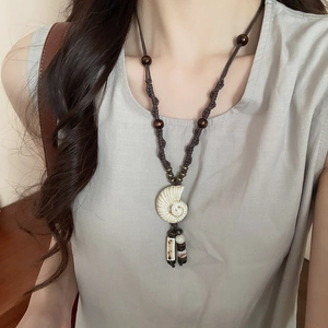 Detail of ethnic pearl flower necklace with conch pendant and bead tassels on woven cord