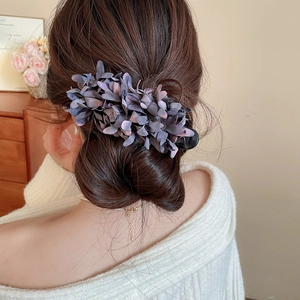 Close-up of elegant mauve fabric flower hair clip worn on a woman's low bun hairstyle
