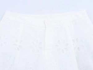 Detailaufnahme weißer Spitzenshorts mit Blumenstickerei und Einzelknopf am Bund