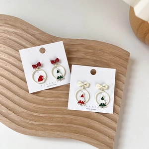 Detailed view of Christmas earrings with red bows and pendants on a wooden tray
