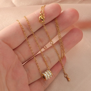 Detail of gold titanium steel necklace with triple-row diamond cylinder pendant on satin