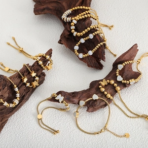 Bracelets à billes plaqués or avec breloques papillon et cœur sur socle en bois