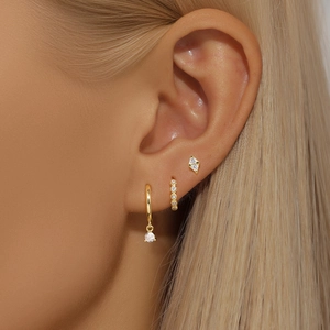 Detail of S925 silver gold-plated hoop earrings and zircon studs on a female model's ear