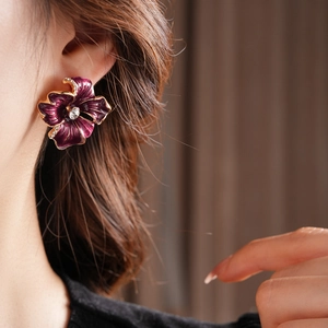 Close-up of vintage purple floral earring with gold trim and diamond on model ear