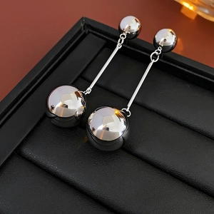 Close-up of silver ball tassel earrings on a black leather jewelry box with metallic finish