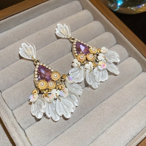 Macro detail of luxury teardrop purple crystal earrings with white floral resin petals