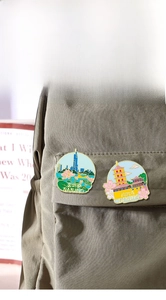 Detailed enamel pins of Nanjing landmarks pinned on a grey canvas bag for decoration