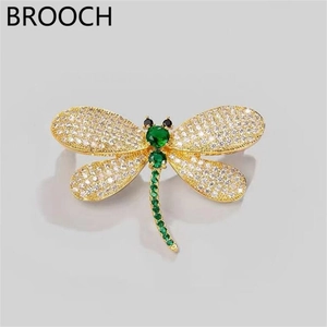 Exquisite dragonfly brooch detail featuring sparkling cubic zirconia and vibrant green stones.
