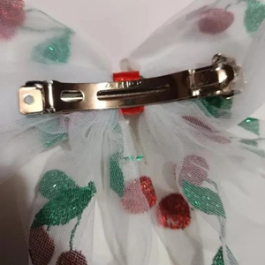 Detail of white mesh bow hair clip with cherry sequins and silver metal spring closure