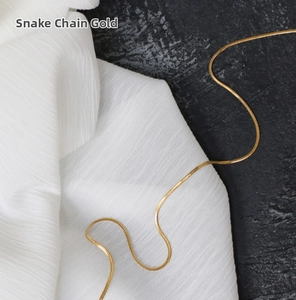 Detailed close-up of golden snake bone chain necklace on elegant textured background
