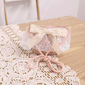 Detailed view of pink straw crossbody bag for girls with large lace bow and woven strap