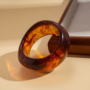 Macro detail of amber resin bangle showing tortoise shell texture and polished finish