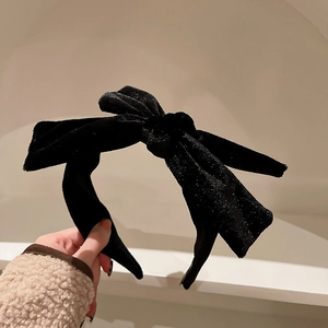 Detailed close-up of a black velvet headband featuring a glittery bow design