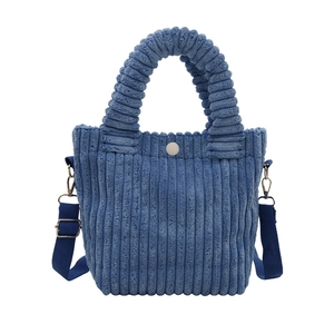 Blue corduroy bucket bag with top handle and shoulder strap in a minimalist design