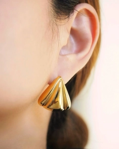 Vue macro détaillée de boucles d'oreilles plissées plaquées or 18k sur un mannequin