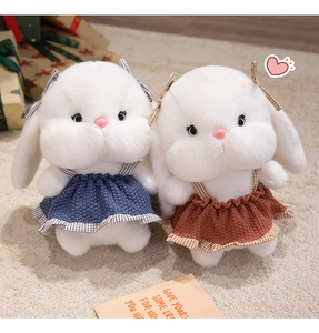 Detail of plush white rabbits in red and blue knitted dresses on a soft rug