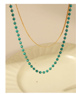 Macro shot of gold flat snake chain and turquoise beaded necklace layering detail