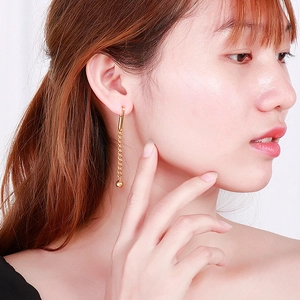 Close-up of golden long tassel chain earrings with bead drop on a model's ear