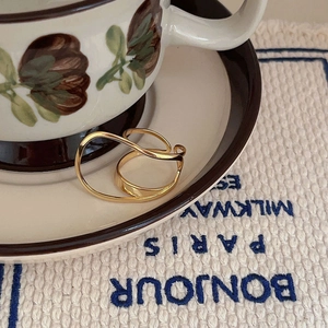 Close-up of a double-layered golden wave ring on a vintage fabric background
