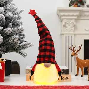 Lighted Christmas gnome plush with red plaid hat on a festive decorated tabletop