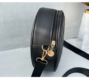 Detail of black quilted round shoulder bag with golden zipper and thick strap