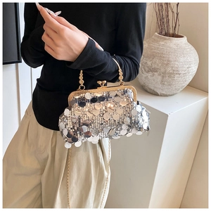Close-up of silver sequin evening bag with gold metal handle and chain strap details