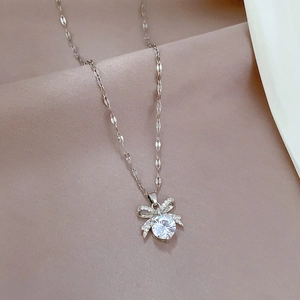 Macro detail of silver bow pendant necklace featuring a sparkling round center gemstone