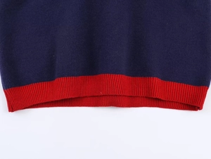 Detail of navy knit sweater with contrast red ribbed hem showing premium stitching