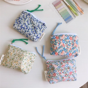 Detailed shot of four floral cotton mini pouches with woven labels and zipper pulls