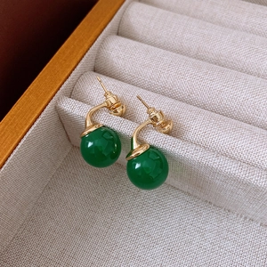 Detail of vintage style green sphere earrings with golden metal studs on a jewelry box