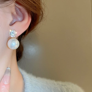 Close-up of model wearing floral zircon earrings with a large round pearl pendant